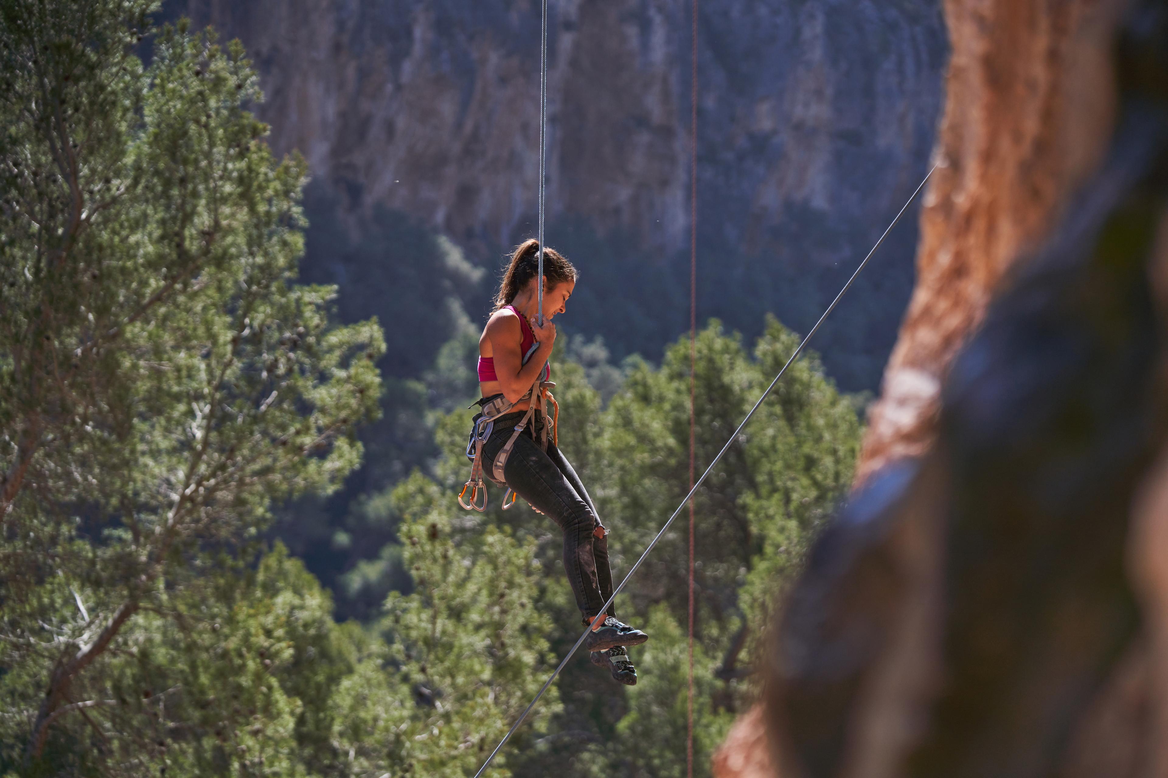 Femme faisant de la descente en rappel dans la montagne